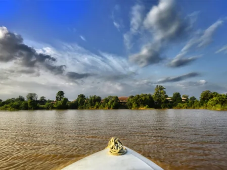 Boat view across the river surrounded by greenery and cloudy sky in Satpura