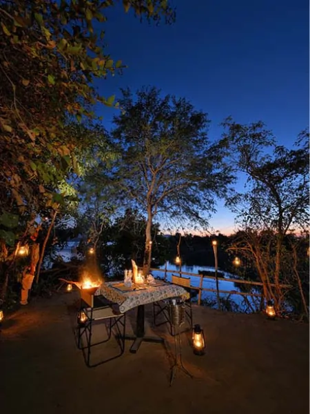Outdoor riverside dining setup surrounded by trees at Denwa Backwater Escape