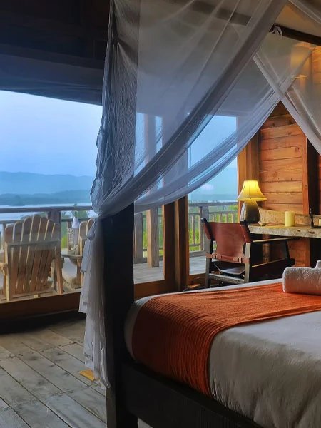 Interior view of a treehouse bedroom with balcony overlooking the Satpura landscape