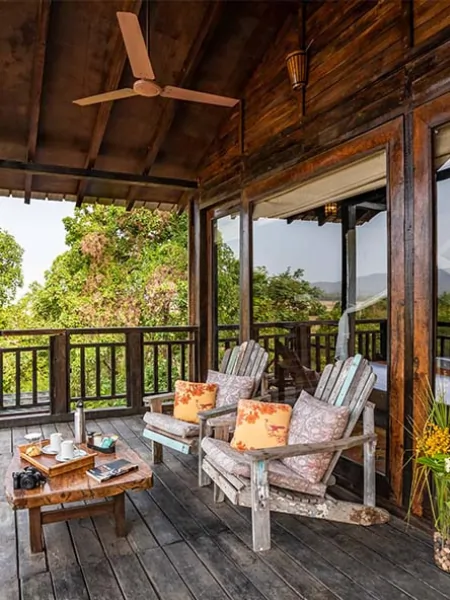 Wooden balcony seating area of a treehouse overlooking lush greenery