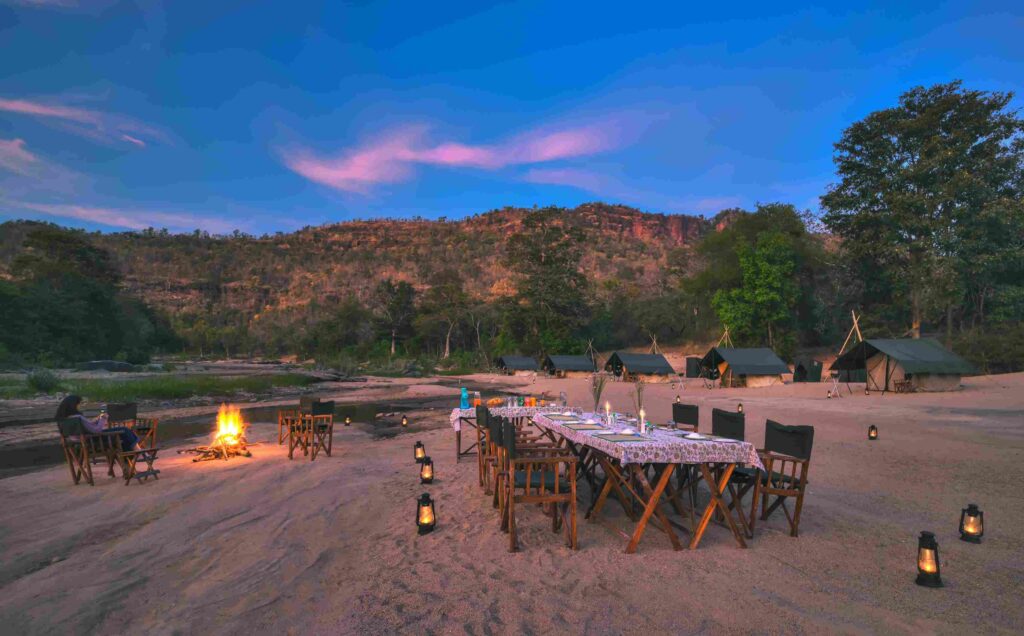 Dining set up at camp, hot shower, lanterns being set up at Denwa Backwater Escapes